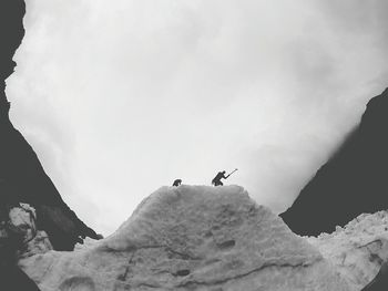 Low angle view of hikers on ice formation at franz josef glacier against sky