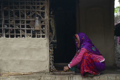 Rural woman in sari grinding spice for food