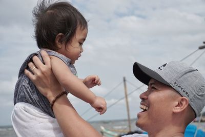 Close-up of father carrying daughter against sky