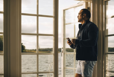 Man looking at camera while standing on window