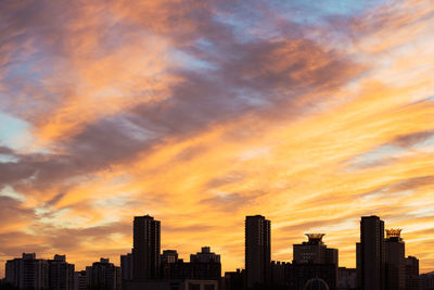 Modern buildings against dramatic sky during sunset