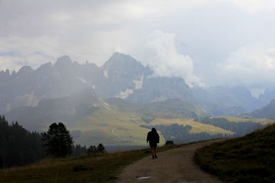 Rear view of man standing on mountain against sky