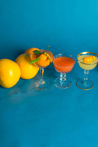 Messy citrus cocktails orange grapefruit lemon on teal blue background
