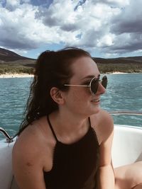 Smiling woman wearing sunglasses in boat against sky
