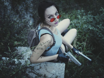 High angle view of woman holding guns sitting outdoors