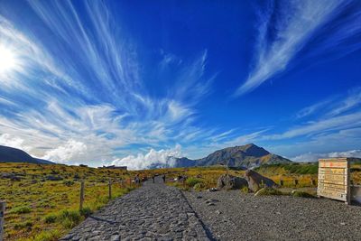 Road leading towards mountains against blue sky