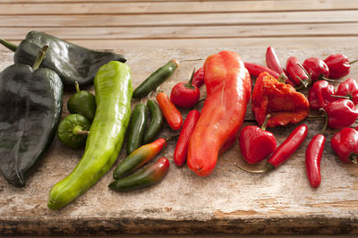 High angle view of various chili peppers on wooden kitchen counter