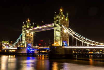 Illuminated bridge over river at night