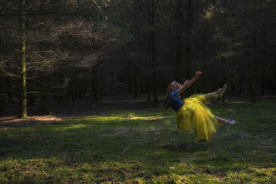 Girl wearing princess costume levitating over field at forest