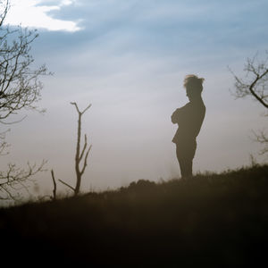 Silhouette man standing on land against sky during sunset