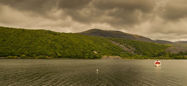 Scenic view of river by mountains against sky