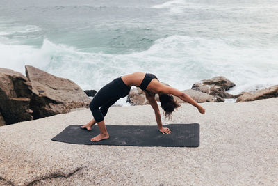 Low section of woman exercising at beach