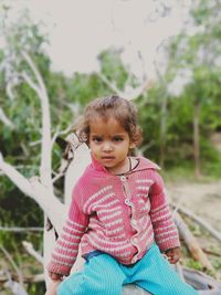 Portrait of girl sitting on fallen tree trunk