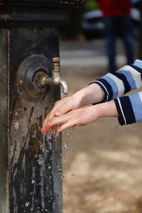 Cropped hand washing hands with water from faucet