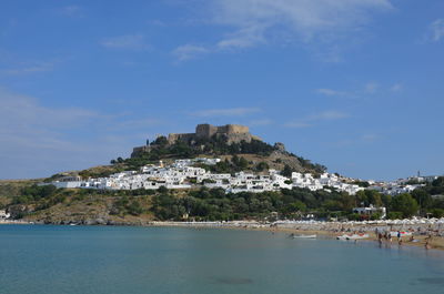 Buildings by sea against blue sky