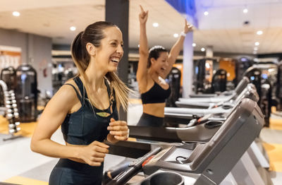 Two happy women working out in gym on a treadmil
