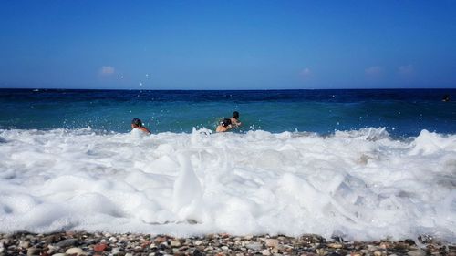 Sea waves rushing towards shore against blue sky