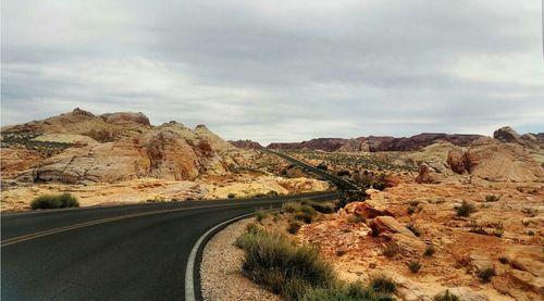 Scenic view of road by mountain against sky