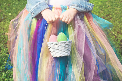 Midsection of woman holding multi colored umbrella