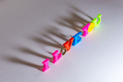 High angle view of colorful alphabets with ring arranged on white background