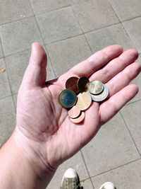 Cropped hand holding coins in sunny day