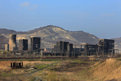 Abandoned building on field by mountain against sky