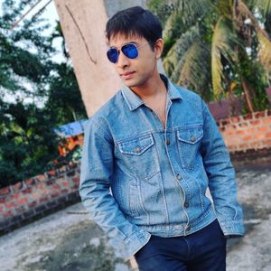 Young man wearing sunglasses standing against trees