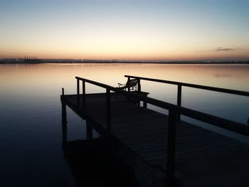 Pier over lake against sky during sunset