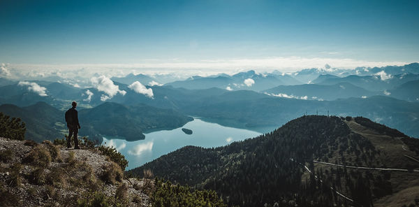 Silhouette mid adult man with backpack standing on mountain against sky