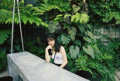 Portrait of young woman sitting on plant