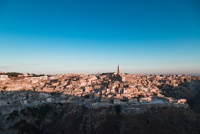 Buildings in city against clear blue sky