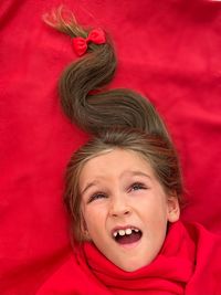 Girl with christmas tree hair making a wish for christmas on the red background with mouth open