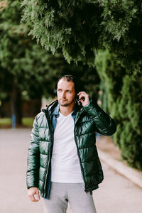 Portrait of young man standing against trees