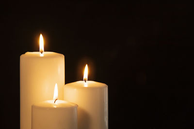 Close-up of lit candle against black background