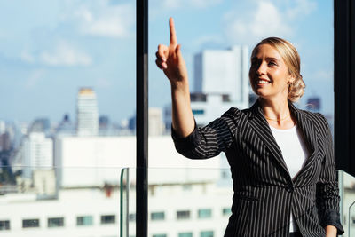 Smiling young woman standing against buildings in city