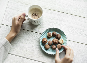 Cropped hand of woman holding coffee on table