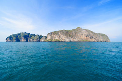 Scenic view of sea and rocks against blue sky