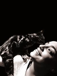 Close-up of woman with dog against black background