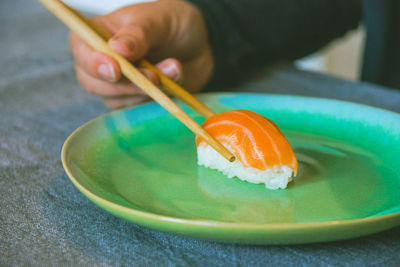 Cropped hand of person holding sushi in plate