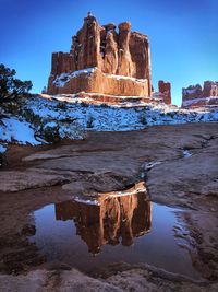 Rock formations by frozen lake against sky