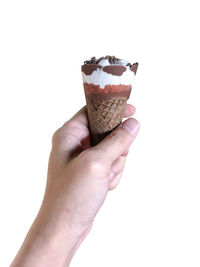 Close-up of hand holding ice cream cone against white background