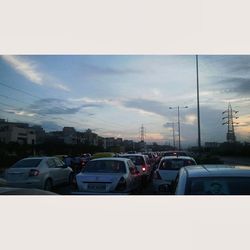 Cars on road against cloudy sky