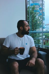 Side view of bearded man drinking coffee at home