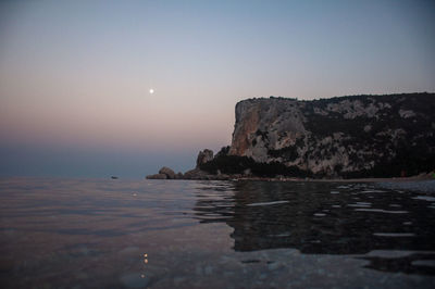 Scenic view of sea and rocks against clear sky