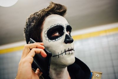 Close-up of man listening to mobile phone with spooky halloween make-up