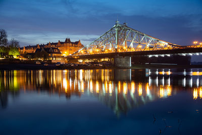 Illuminated bridge over river against sky at night