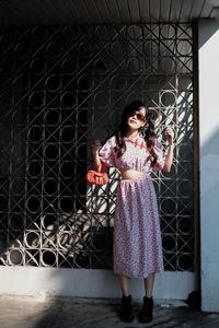 Portrait of smiling young woman standing against wall