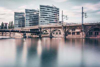 River by bridge against buildings in city