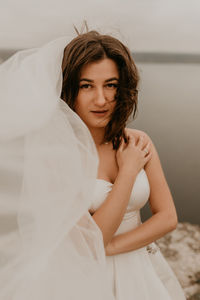 Portrait of young woman sitting on bed at home