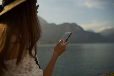 Rear view of woman using mobile phone in water